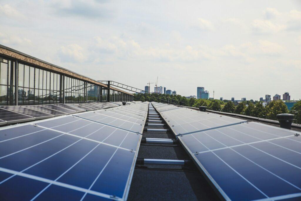 Nahaufnahme einer Photovoltaikanlage auf einem Dach in Köln, mit Blick auf die Skyline der Stadt im Hintergrund, zeigt die Nutzung von Solarenergie in urbanen Gebieten und die Bemühungen zur Reduzierung der CO2-Emissionen.