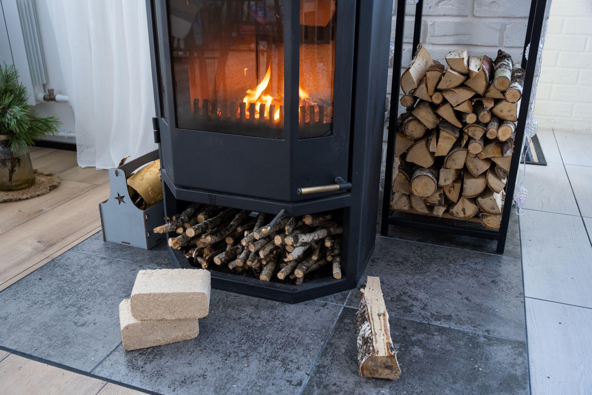 Kamin mit loderndem Feuer und gestapeltem Brennholz