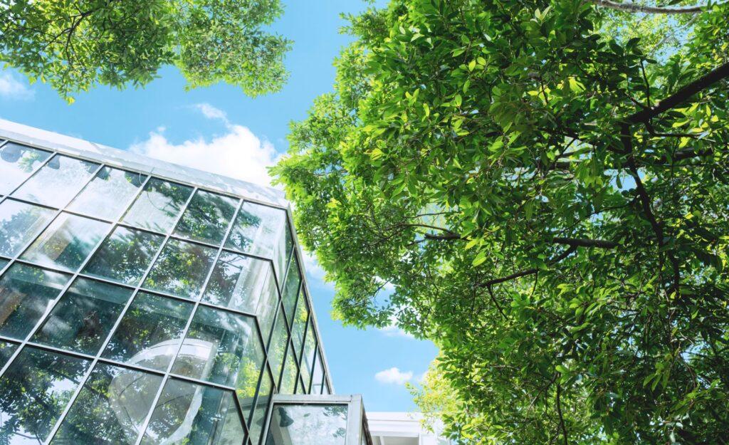 Glasgebäude mit grünen Bäumen und blauem Himmel