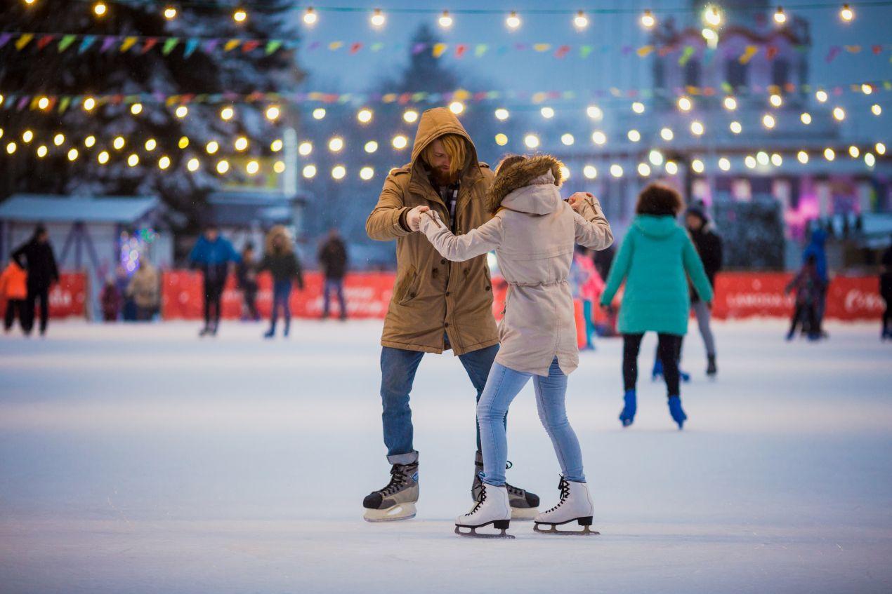 Paar mit Winterjacken faehrt gemeinsam auf Eisbahn – Bauer Schlittschuhe fuer sicheren Stand beim Eislaufen in der Freizeit