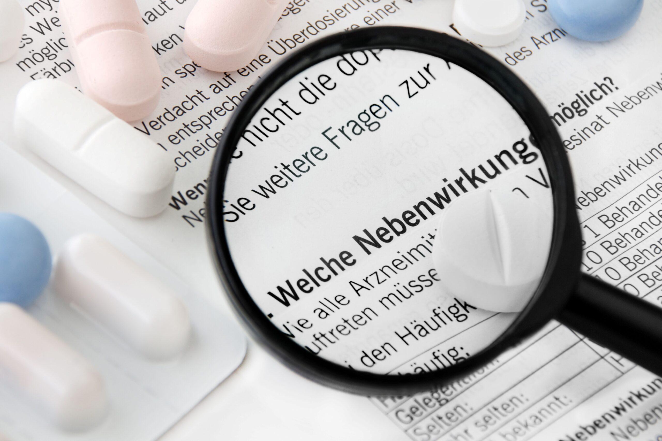 Beipackzettel mit dem Wort „Nebenwirkungen“ unter einer Lupe, daneben Tabletten – Symbolbild für Sicherheit und Verträglichkeit von Griffonia