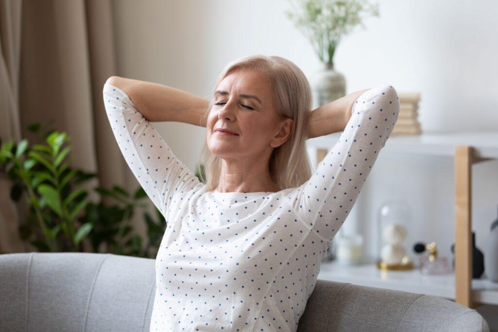 Ältere Frau entspannt auf dem Sofa mit geschlossenen Augen – Symbolbild für natürliche Stressbewältigung und innere Ruhe durch Griffonia